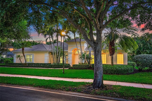 view of front of home featuring stucco siding and a yard