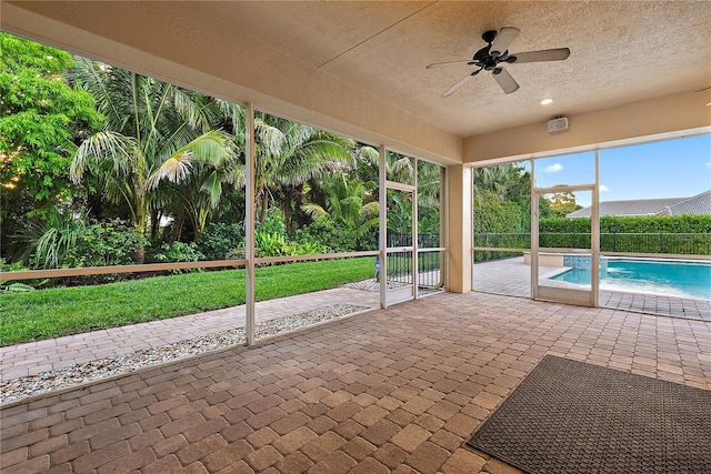 unfurnished sunroom featuring ceiling fan