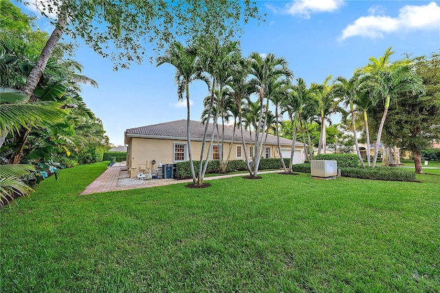 rear view of property with a lawn, a patio, stucco siding, and a tile roof