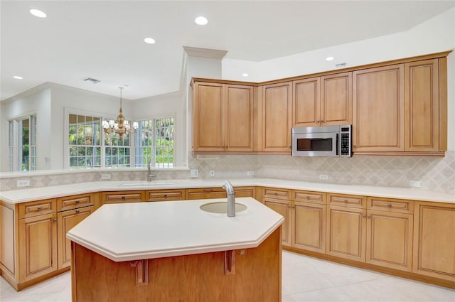 kitchen with light countertops, light tile patterned floors, stainless steel microwave, and a sink