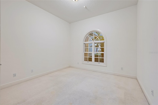carpeted empty room featuring baseboards and a textured ceiling
