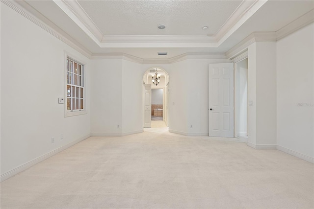 unfurnished room featuring carpet floors, ornamental molding, a tray ceiling, and an inviting chandelier