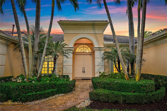 entrance to property featuring stucco siding and a tile roof