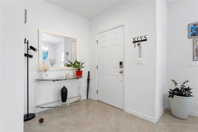 foyer with light tile floors and an inviting chandelier