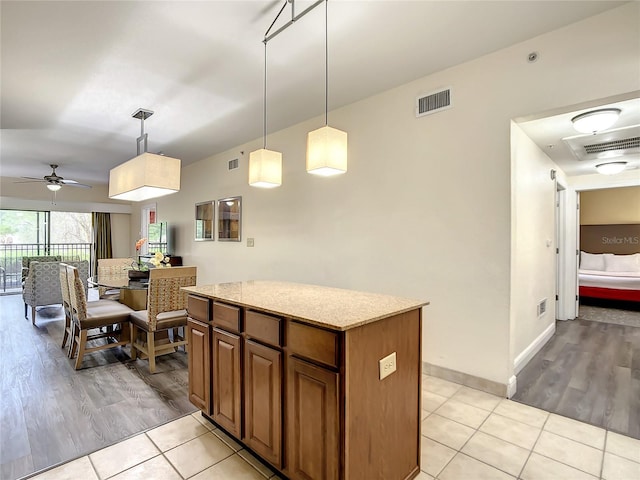 kitchen featuring light stone countertops, ceiling fan, pendant lighting, and light tile floors