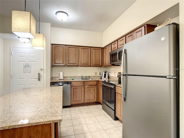 kitchen with pendant lighting, light tile floors, appliances with stainless steel finishes, sink, and light stone counters