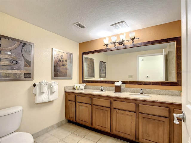 bathroom with an inviting chandelier, tile floors, a textured ceiling, toilet, and double vanity