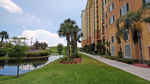 view of property's community with a lawn and a water view