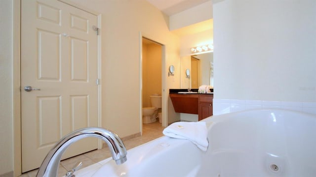 bathroom with toilet, large vanity, tile floors, and a bathtub