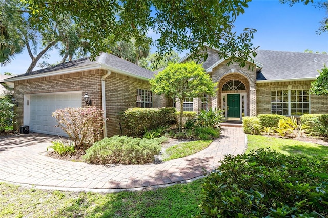 view of front of home featuring brick siding, decorative driveway, a garage, and roof with shingles