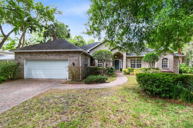 ranch-style home featuring decorative driveway, a front yard, brick siding, and an attached garage