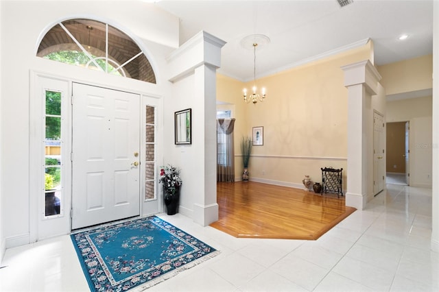 entrance foyer with tile patterned flooring, plenty of natural light, crown molding, and a chandelier