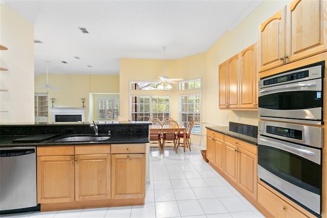 kitchen with light tile flooring, ceiling fan, dark stone countertops, appliances with stainless steel finishes, and sink