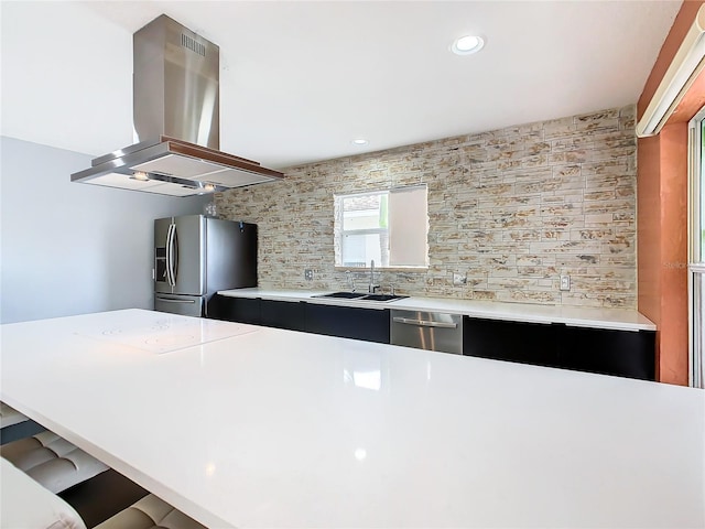 kitchen featuring sink, island exhaust hood, appliances with stainless steel finishes, backsplash, and a breakfast bar area