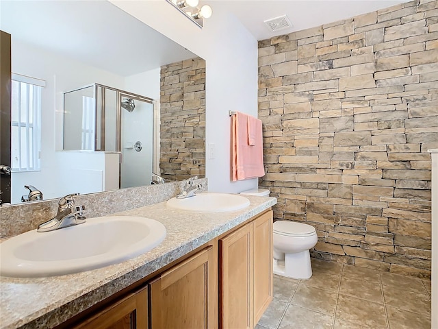 bathroom featuring double vanity, toilet, tile floors, and a shower with shower door