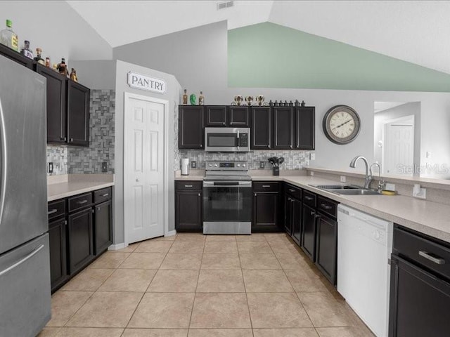 kitchen with light tile patterned flooring, sink, appliances with stainless steel finishes, decorative backsplash, and lofted ceiling