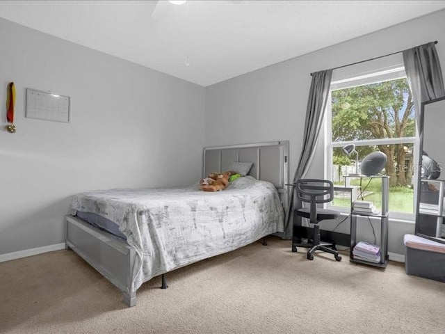 bedroom featuring ceiling fan, light carpet, and multiple windows