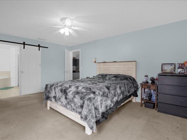 bedroom featuring ceiling fan, a barn door, and light colored carpet