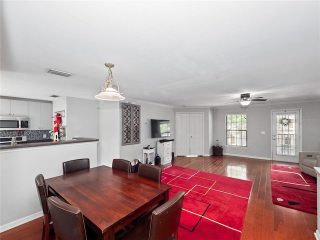 dining space with ceiling fan, dark hardwood / wood-style floors, and ornamental molding