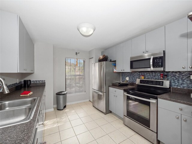 kitchen featuring appliances with stainless steel finishes, light tile patterned floors, gray cabinetry, and sink