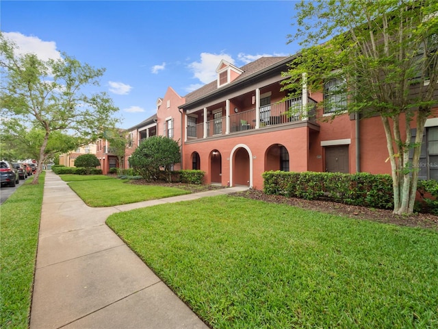 view of front of house with a balcony and a front lawn