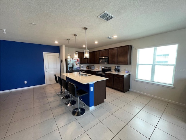 kitchen with an island with sink, sink, appliances with stainless steel finishes, a breakfast bar area, and decorative light fixtures