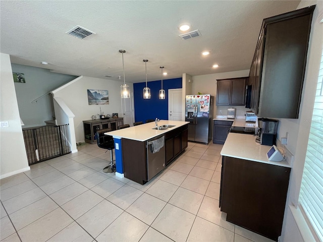 kitchen featuring a kitchen breakfast bar, decorative light fixtures, a center island with sink, appliances with stainless steel finishes, and sink