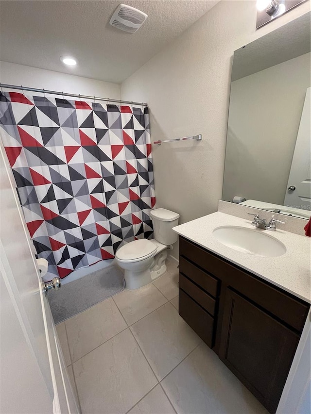 bathroom with toilet, a textured ceiling, vanity with extensive cabinet space, and tile flooring