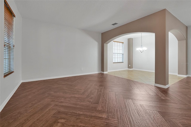 unfurnished living room with light parquet floors, a notable chandelier, and a textured ceiling