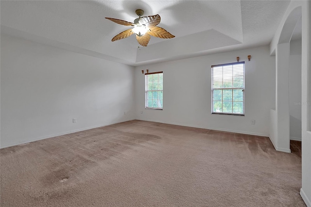 carpeted spare room with ceiling fan, a tray ceiling, and a textured ceiling