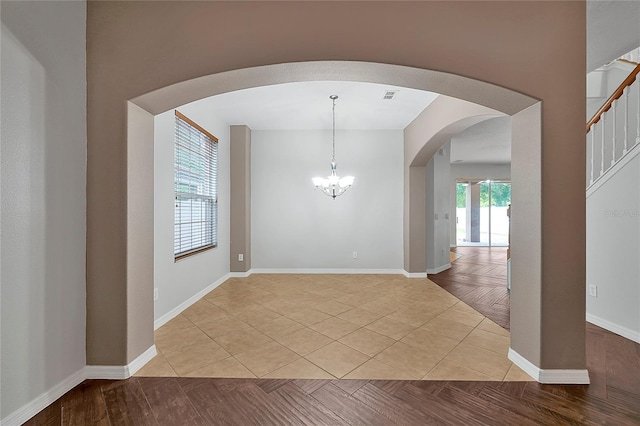 spare room with light tile patterned flooring and a notable chandelier