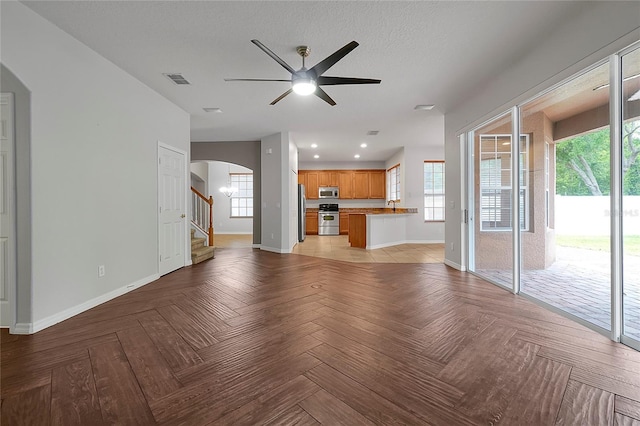 unfurnished living room with ceiling fan, a textured ceiling, and light parquet flooring