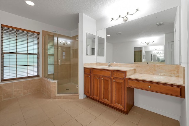 bathroom with a shower with door, vanity, tile patterned floors, and a textured ceiling