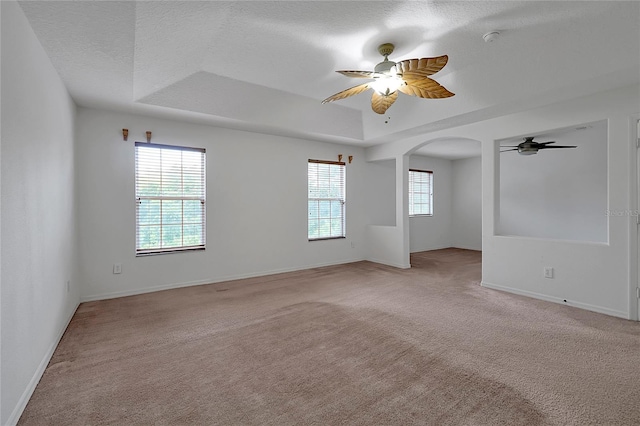 carpeted empty room featuring ceiling fan, a raised ceiling, and a textured ceiling