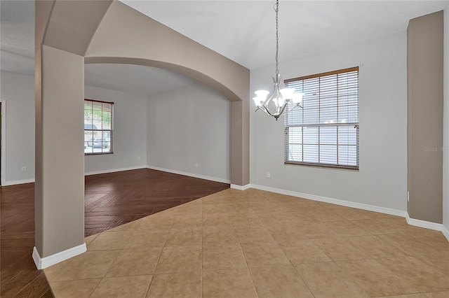 spare room with a notable chandelier and light parquet floors