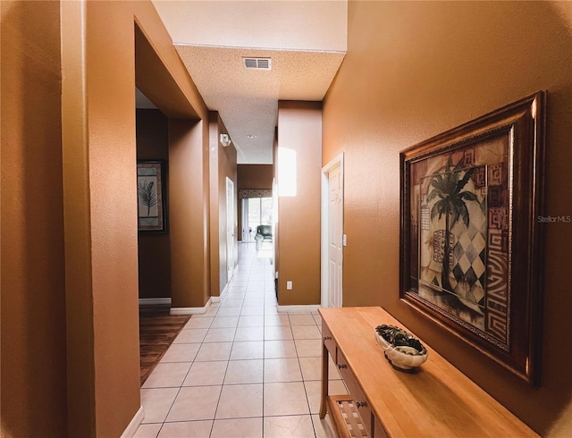 hallway featuring a textured ceiling and light tile flooring