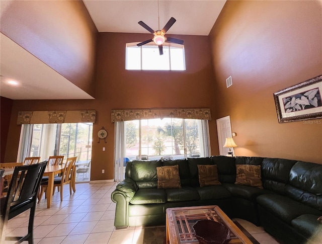 tiled living room with ceiling fan and a towering ceiling