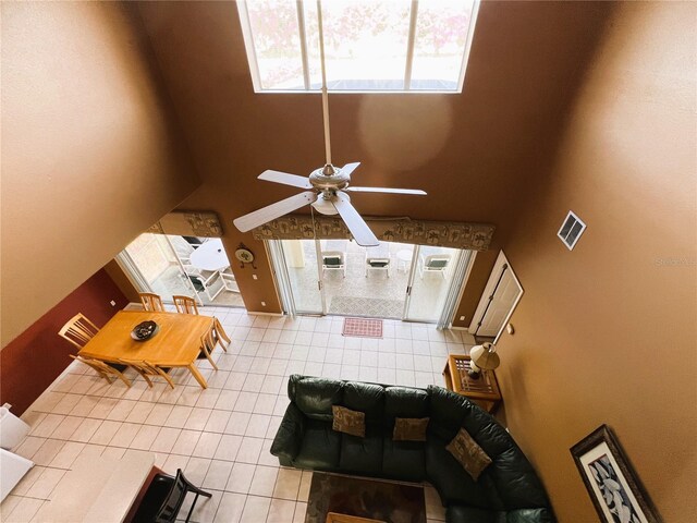 tiled living room featuring ceiling fan and a towering ceiling