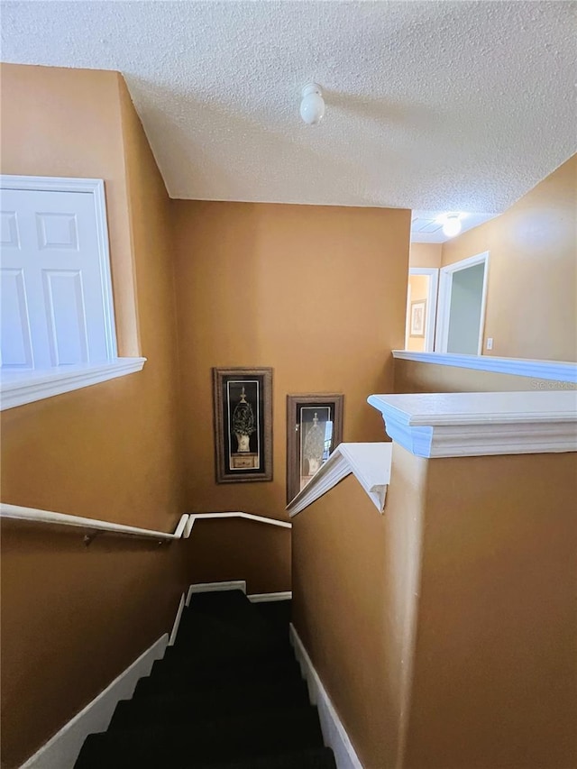 staircase featuring a textured ceiling