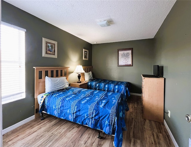 bedroom with a textured ceiling and wood-type flooring