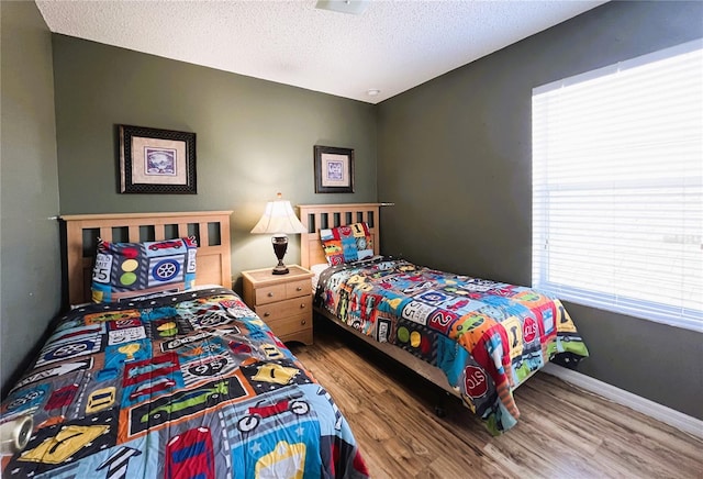 bedroom with light hardwood / wood-style floors, a textured ceiling, and multiple windows