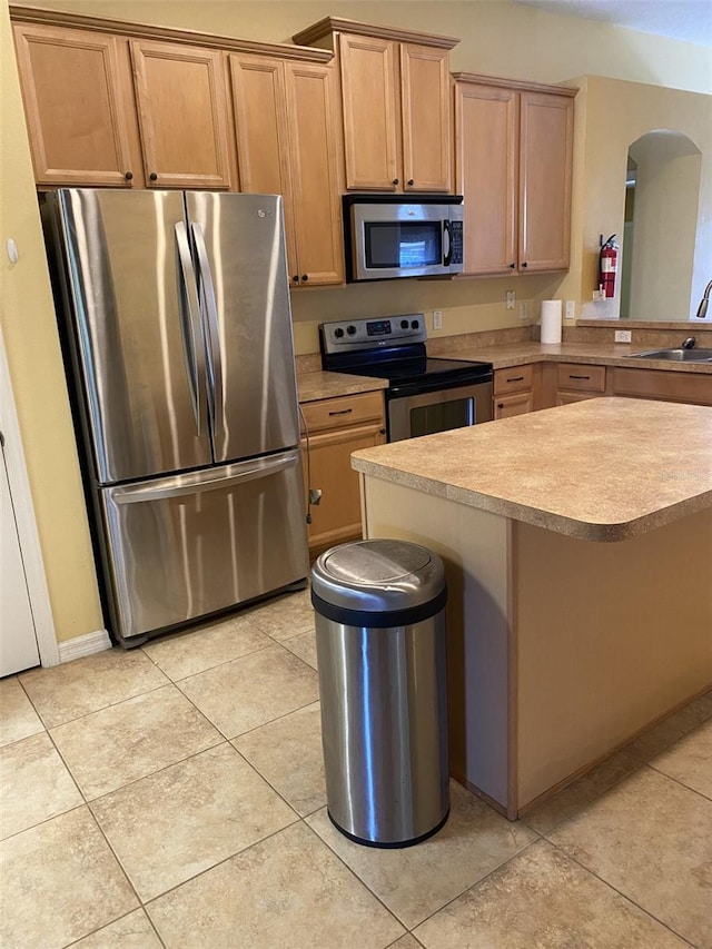 kitchen with sink, kitchen peninsula, a kitchen bar, light tile patterned floors, and appliances with stainless steel finishes