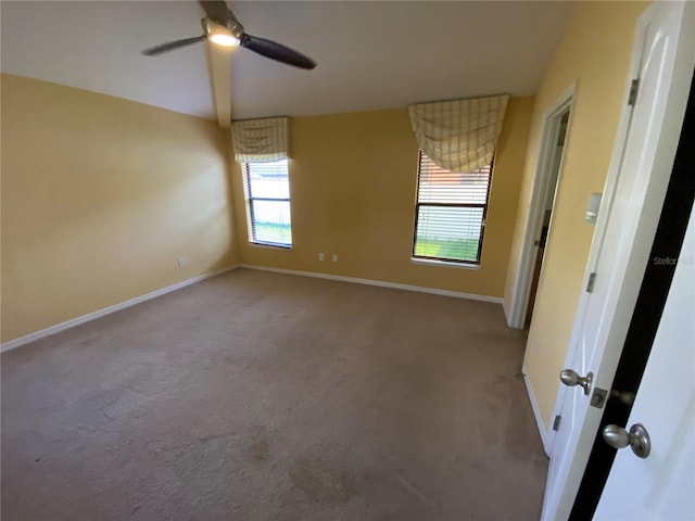 carpeted empty room with ceiling fan and a wealth of natural light