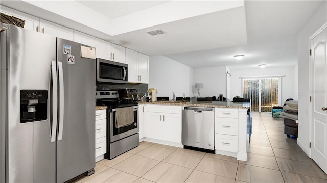 kitchen featuring white cabinets, appliances with stainless steel finishes, light stone countertops, and kitchen peninsula