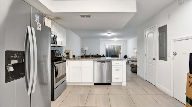 kitchen with light stone counters, kitchen peninsula, appliances with stainless steel finishes, and white cabinetry