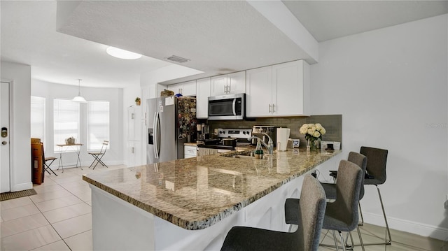 kitchen with a kitchen breakfast bar, stainless steel appliances, kitchen peninsula, and white cabinetry