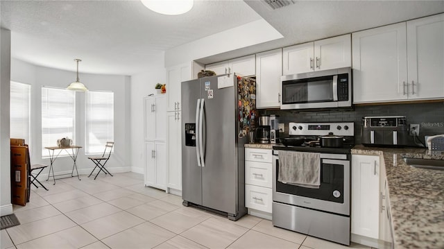 kitchen with decorative light fixtures, tasteful backsplash, white cabinets, light tile floors, and stainless steel appliances