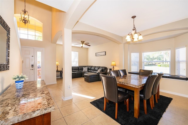 tiled dining space with ceiling fan with notable chandelier