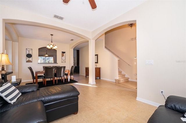 tiled living room featuring ceiling fan with notable chandelier