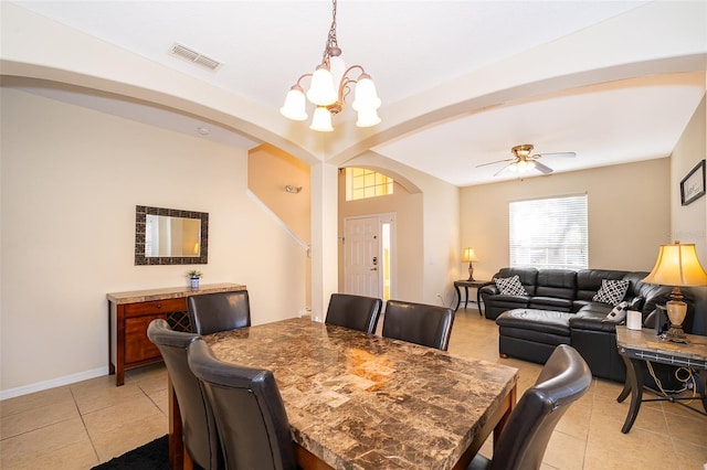 tiled dining room with ceiling fan with notable chandelier